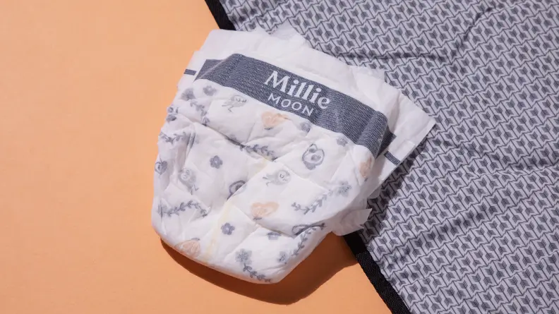 A single Millie Moon diaper sitting on the edge of a changing mat.