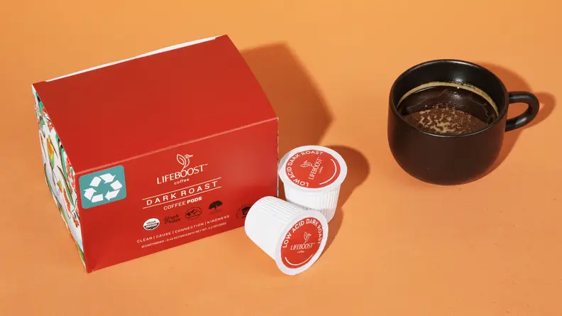A red box of Lifeboost Coffee's pods and a black cup of coffee next to it, on an orange background.