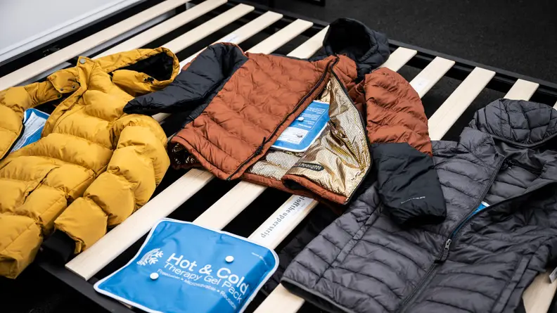 Three jackets lay with heating pads wrapped inside of them, which are used to measure the rate at which heat is lost in each piece.