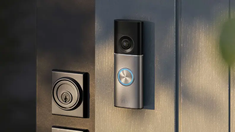 Silver and black ring camera on a wood wall next to a door