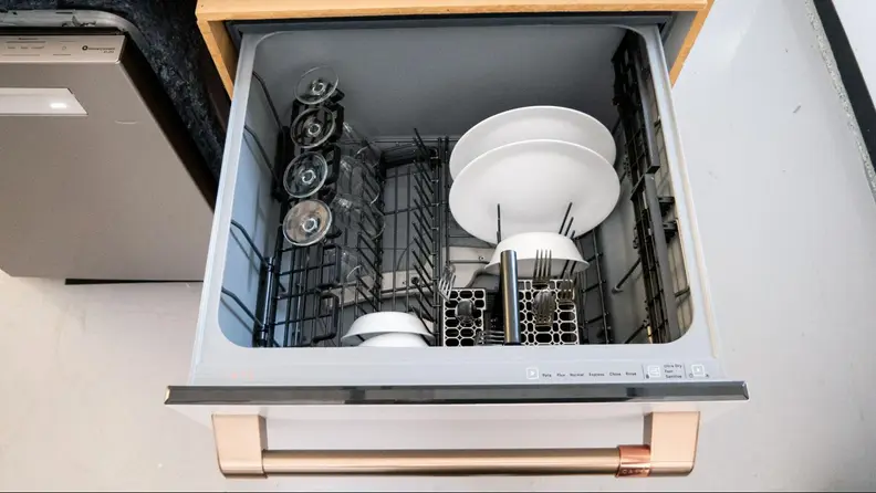 A close-up of the dishwasher's top drawer, which has a rack and a few plates, bowls, and wine glasses stowed.