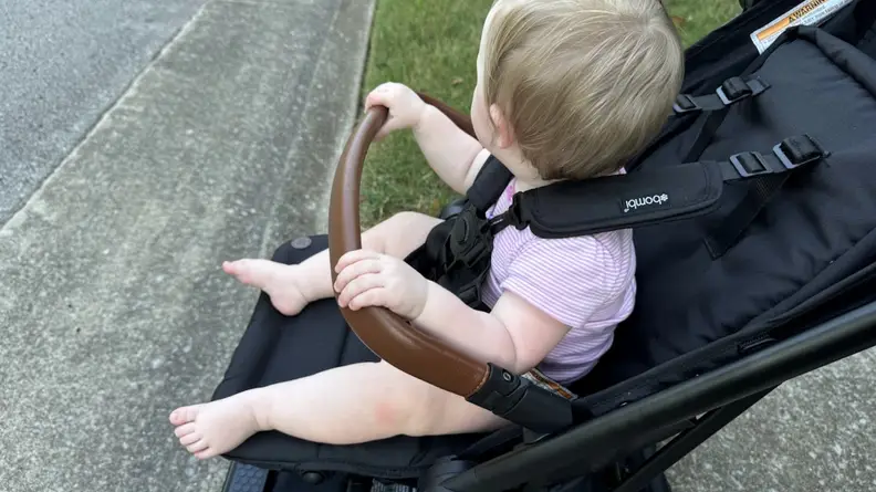 Baby grabbing handlebar of the Bombi Bebee Stroller