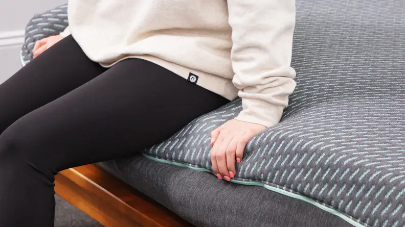 A person sitting on the edge of the Tuft & Needle Mint hybrid mattress.