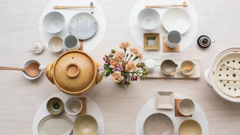 A top-down photo of a set table with a donabe clay pot in the center.