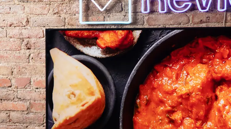 A TCL QM8 LED TV showing food being cooked onscreen with vibrant colors.
