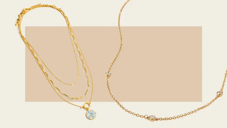 Two gold necklaces against an abstract tan-colored background.