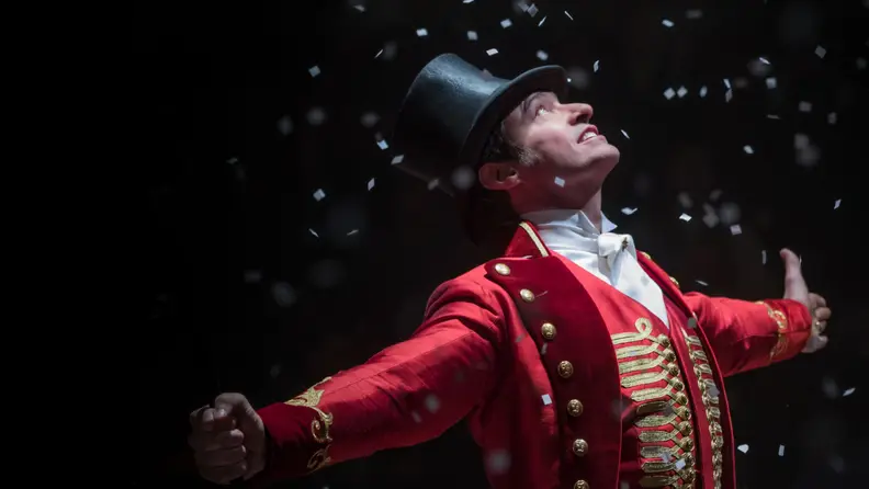 A still from 'The Greatest Showman' featuring Hugh Jackman standing in the middle of a group of performers.