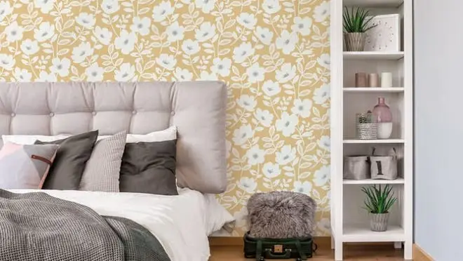 Bed with gray headboard against yellow floral wall