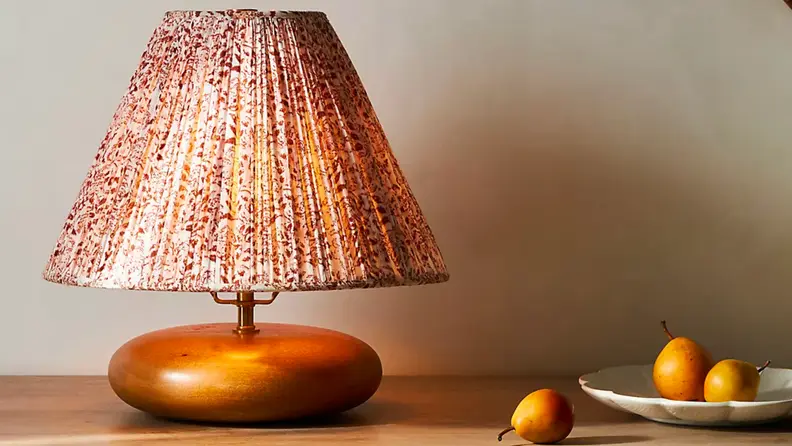 Close up of a brass lamp with a pink shade.