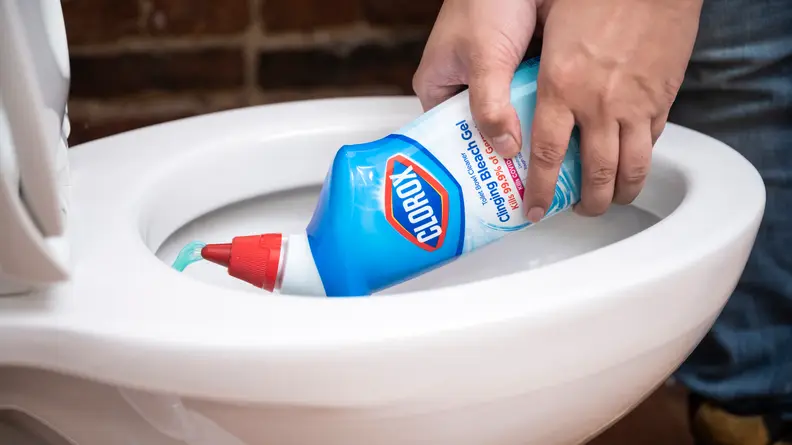 A person squirts liquid cleaner into the bowl of a toilet
