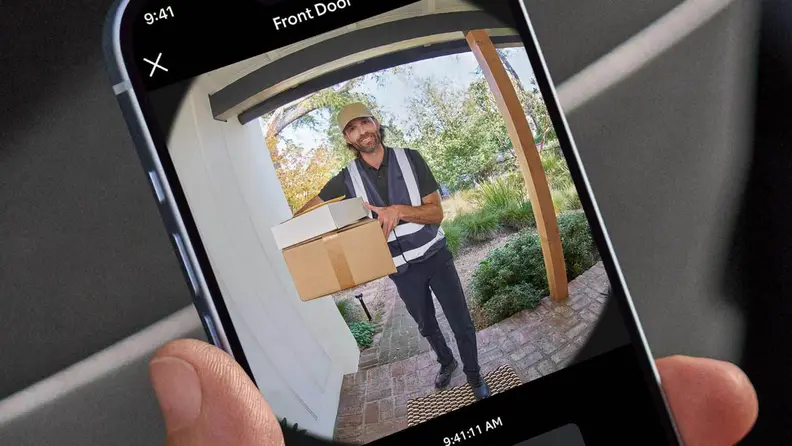 A hand holding a phone that shows the Ring app open to the view from the new Ring Battery Doorbell.