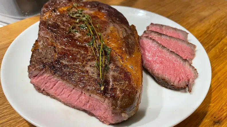 Ribeye steak on plate with a pink center.