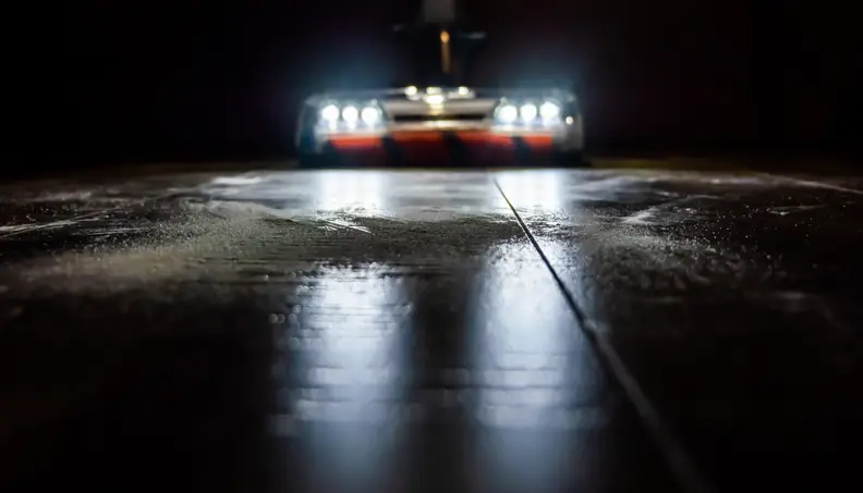 A vacuum with LED lights cleans the floor in a dark room