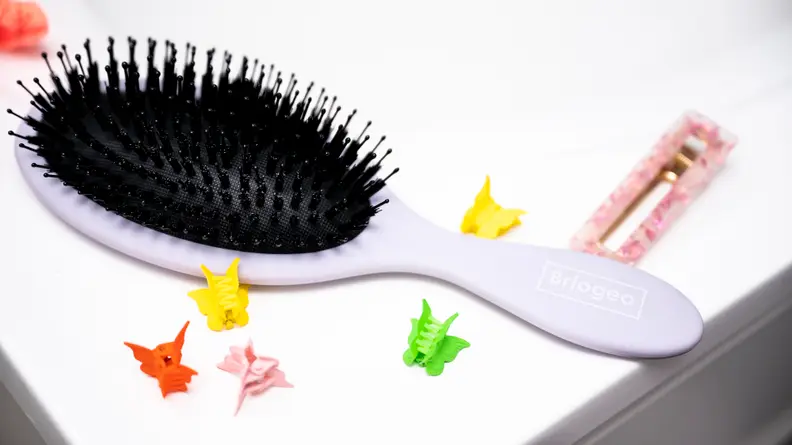 One of the best hair brushes sitting on a sink surrounded by colorful butterfly hair clips,