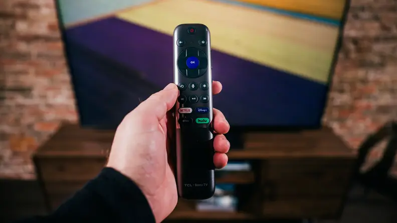 The TCL 6-Series' Roku Remote control being held in front of the screen