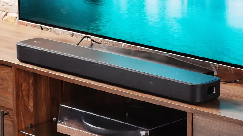 The HT-S2000 soundbar on a wood entertainment center next to a TV.