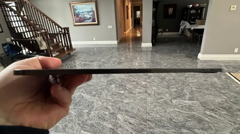 Side shot of a person holding up the iPad Pro, showing how thin it is.