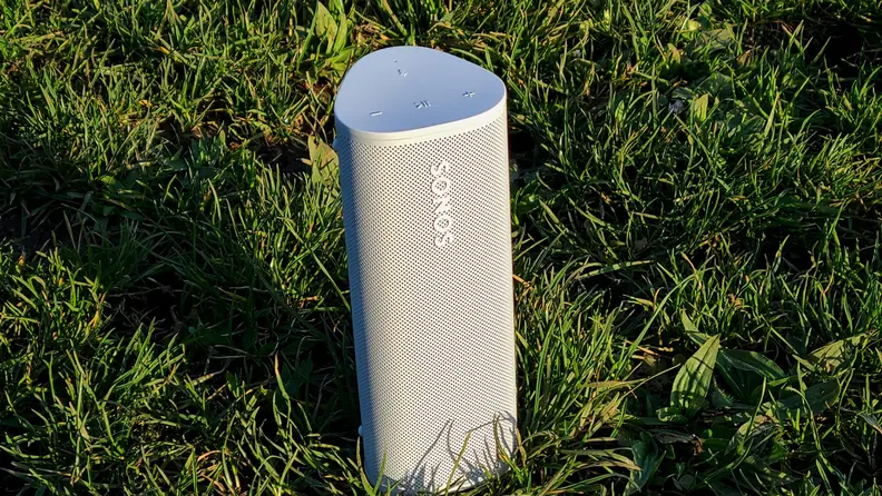 The white and tubular Sonos Roam set upright in a field