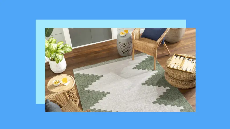 A cream and green rug on a patio against a blue background.