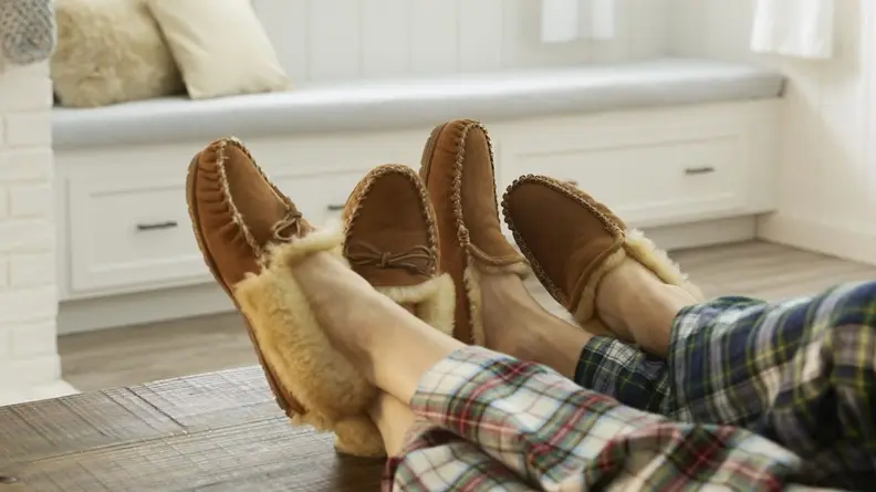 A couple wearing L.L. Bean Wicked Good slippers, one in venetian style, the other in moccasin.