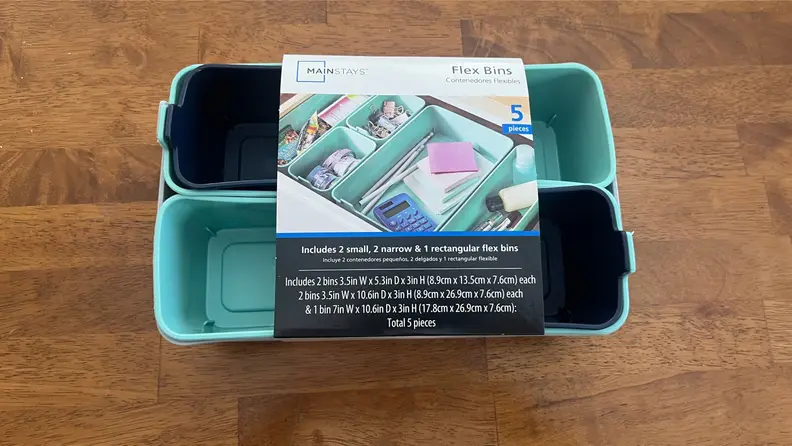 Two small silicone drawer organizers packaged together sitting on a wood table.