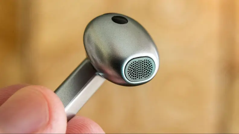 Close-up of one of the earbuds being held up by a hand.