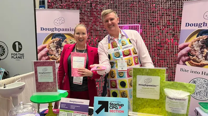 Two people holding Doughpamine products in front of a display