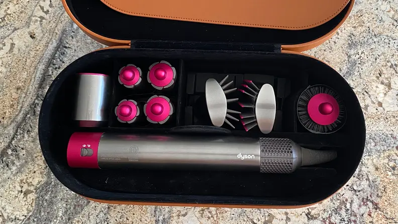 The Dyson Airwrap Styler attachments inside its brown leather case.