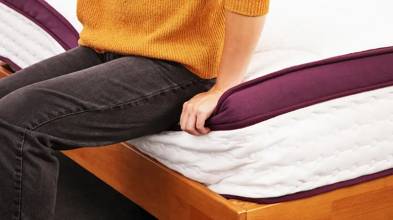 A person sitting on the compressed edge of the Awara Premier mattress.