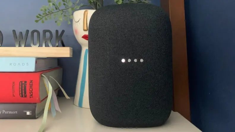 Google's Nest Audio smart speaker sits on a bookshelf.