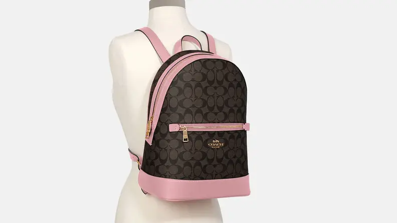 A brown and pink Coach backpack on a mannequin.