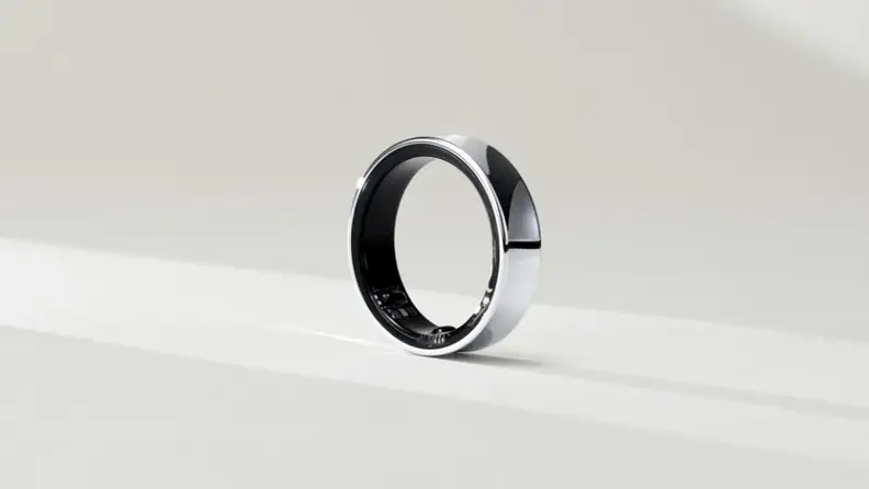 A silver wearable ring sitting on a white surface.