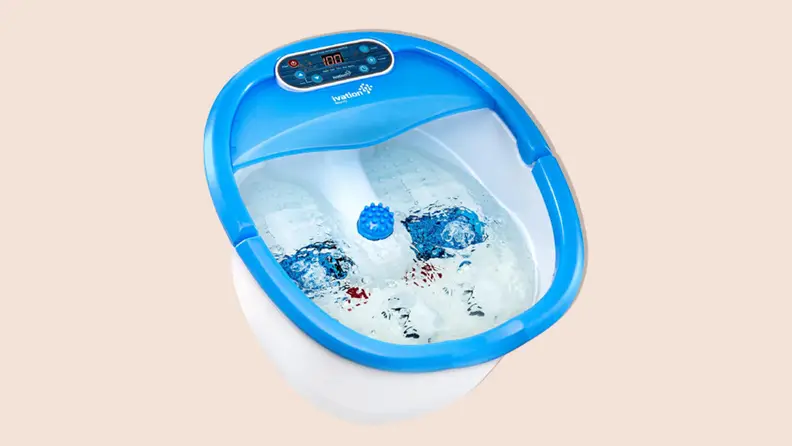 Product shot of a blue and white Ivation Foot Spa filled with water and bubbles on a tan background.