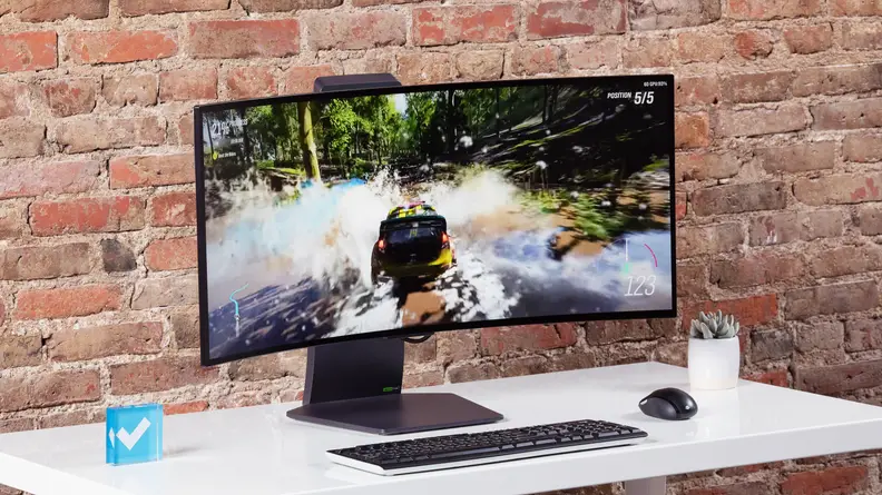 The LG UltraGear OLED 34GS95QE-B, a 34-inch curved ultrawide monitor on a silver aluminum stand against a brick wall