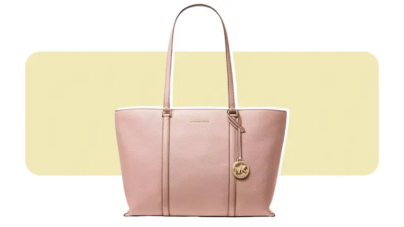 A large leather tote with a gold charm hanging off of one of its straps.