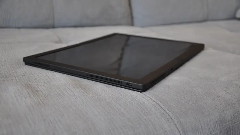 The all-black fold is fully extended, sitting on a grey couch like a tablet.