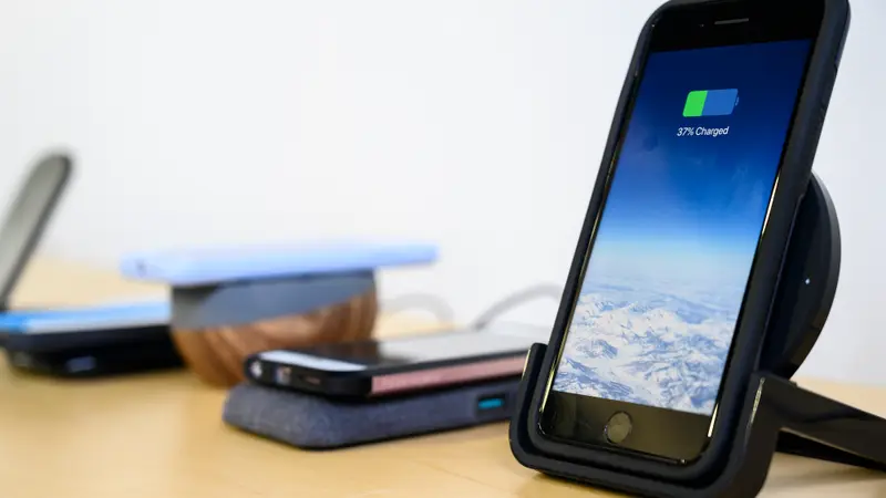 An iPhone charging in an upright charger
