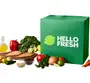 Prepared plates, a hand holding a phone displaying a meal kit app, and a meal kit box on a green background