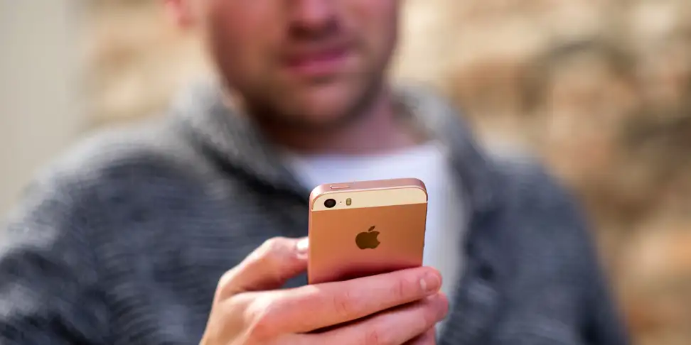 A man using an iPhone SE to read