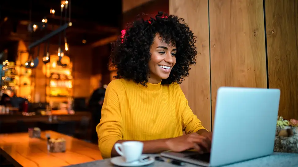 A photo of a woman on her laptop at a coffee shop.