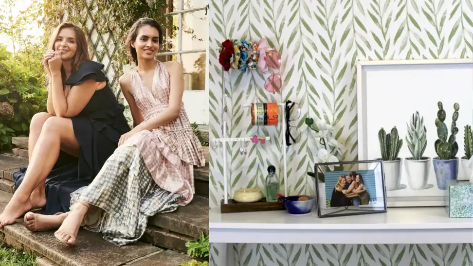 Two women sitting on porch next to green and white wallpaper behind a desk