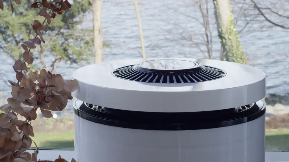 CleanAirZone bio-based air purifier in front of an outdoor landscape of trees and water