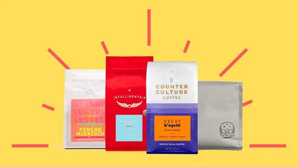 Four colorful bags of decaf coffee against a bright yellow background.