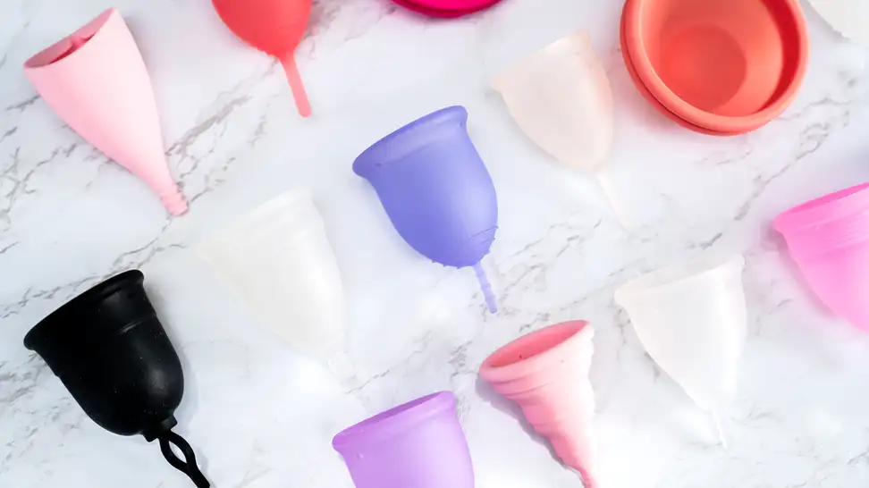 colorful menstrual cups on white marble background