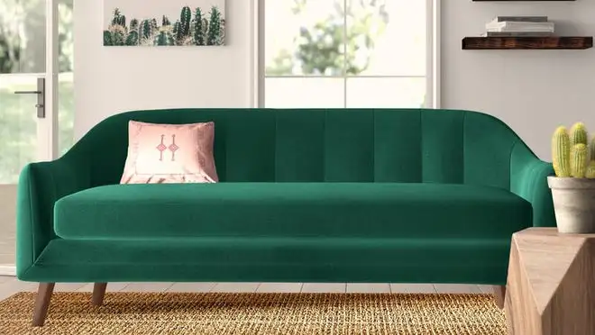 Emerald colored couch with pink pillow sitting in modern styled living room.