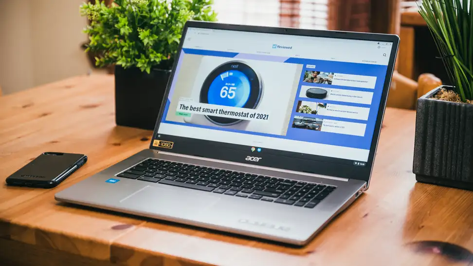 An open laptop on a desk with a small plant on both sides