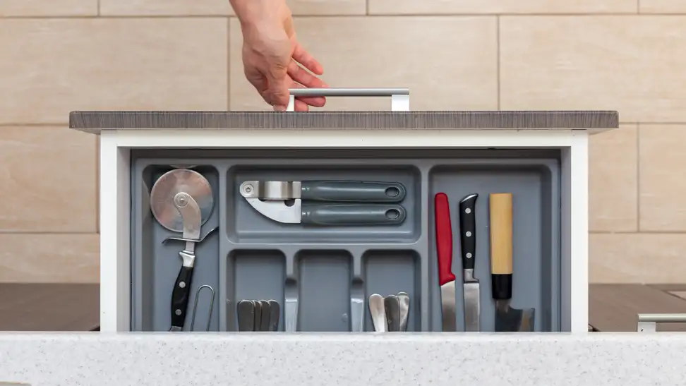 A drawer of kitchen utensils being opened.