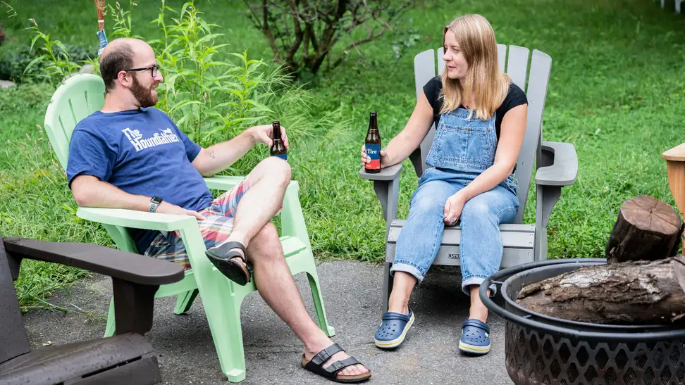 Man and woman sitting in adirondack chairs talking.