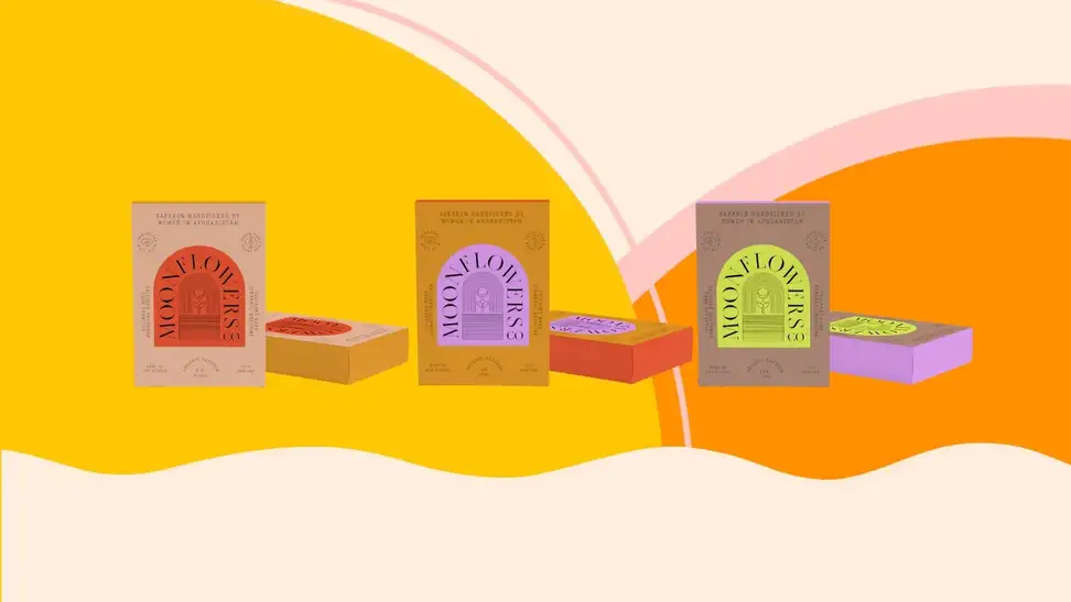 Three small boxes of saffron arranged in a straight horizontal line on a colorful yellow and orange background.
