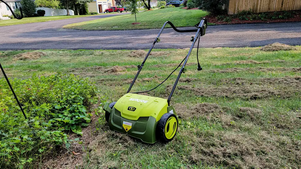 A dethatcher sits on a lawn with grass clippings around it